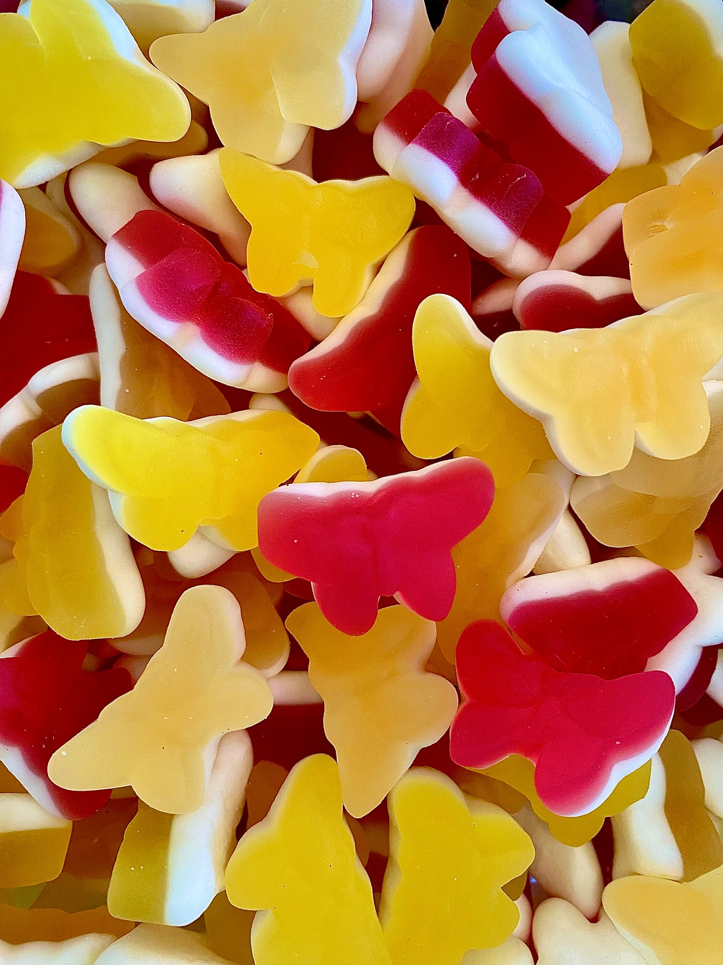 Assorted butterfly-shaped gummy candies in red, yellow, and white. Swedish candy