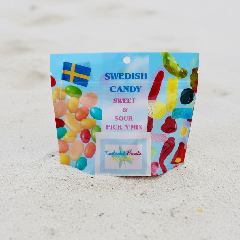 A resealable stand-up pouch of Swedish candy, labeled 'Swedish Candy Sweet & Sour Pick N Mix' with colorful illustrations of gummy candies and Swedish flags, standing upright on a light sandy surface.