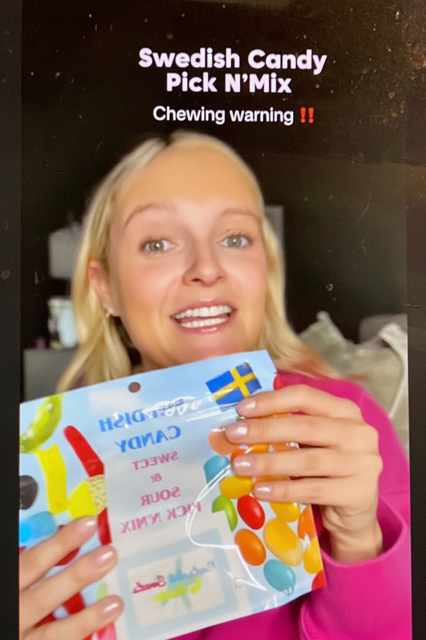 Person holding a Swedish candy package with text 'Swedish Candy Pick N' Mix Chewing warning!!' and a brand name.