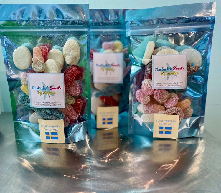 Three packages of gummy candy with visible branding on a reflective surface