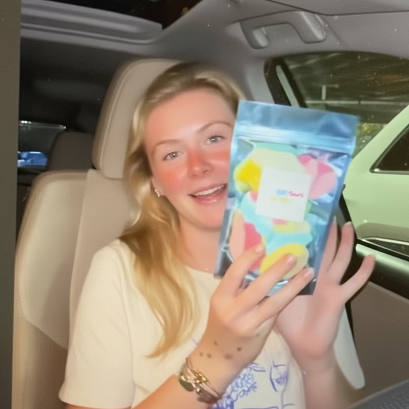 Person sitting in a car holding a colorful package with text 'We Love' displayed above.