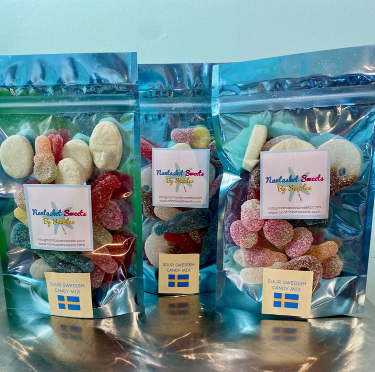 Three packages of Swedish candy with visible branding on a reflective surface.