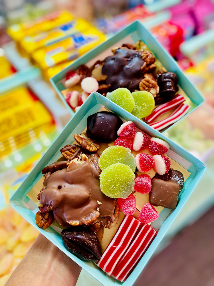 Two small boxes filled with assorted candies and chocolates on a colorful background.