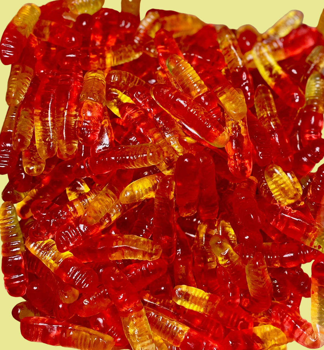 Close-up of red and orange gummy worms on a white surface