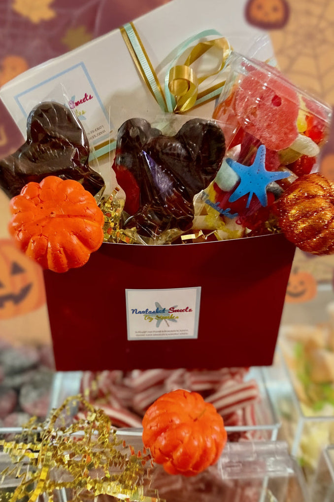 Halloween-themed candy box with gummy worms, pumpkins, and other treats on a Halloween-themed background.