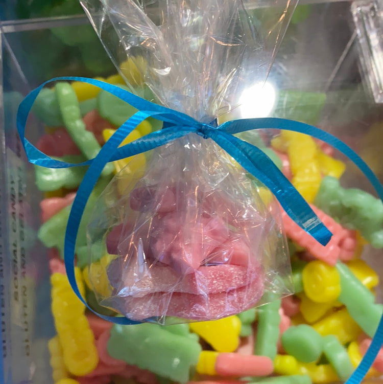 Candy bags tied with a ribbon, set against a tropical beach background.